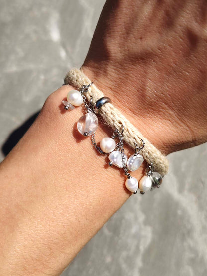 Frau trägt handgestricktes Seide-Hanf-Armband mit Bergkristall und Perlen am Handgelenk, fotografiert im Sonnenlicht