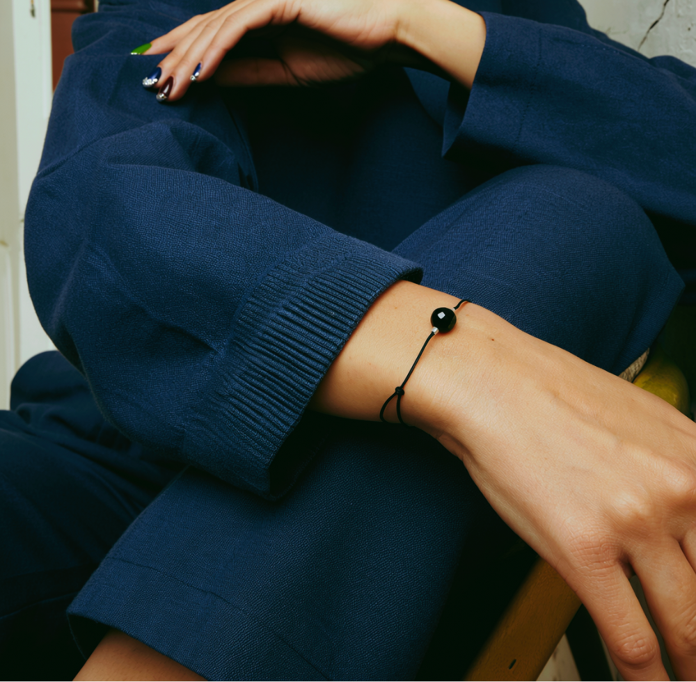 Frau mit blauem Leinenanzug trägt schlichtes Armband mit schwarzem Stein und Silber